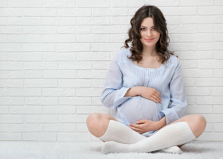 Беременная женщина сидит в позе лотоса